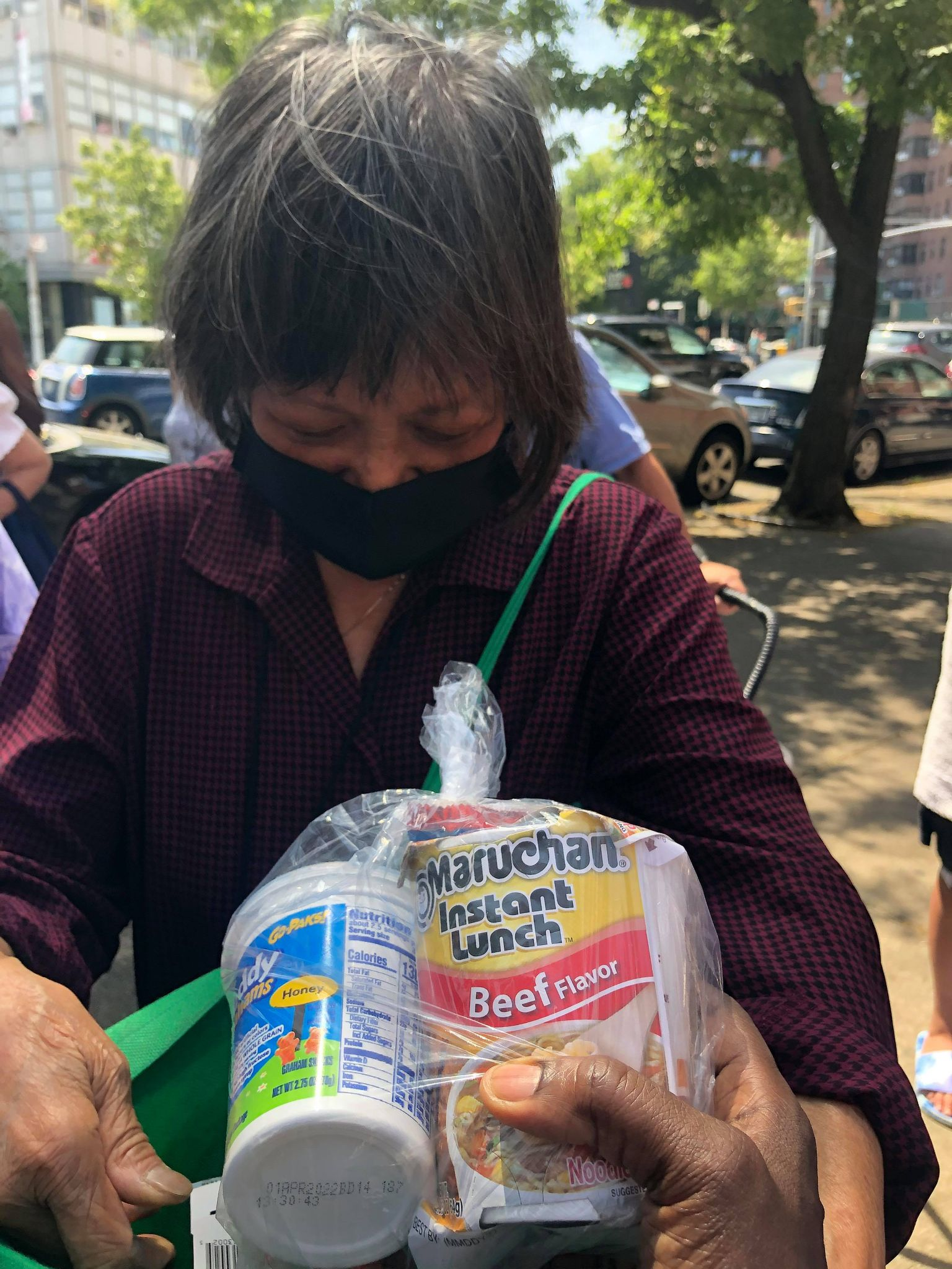 Community member receiving canned goods and noodles in a bag outdoors